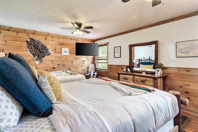 bedroom with a textured ceiling, wainscoting, a ceiling fan, and wooden walls