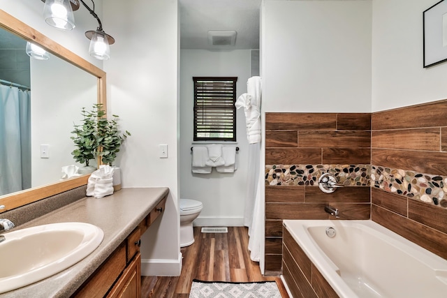 full bathroom with visible vents, toilet, wood finished floors, a bathtub, and vanity