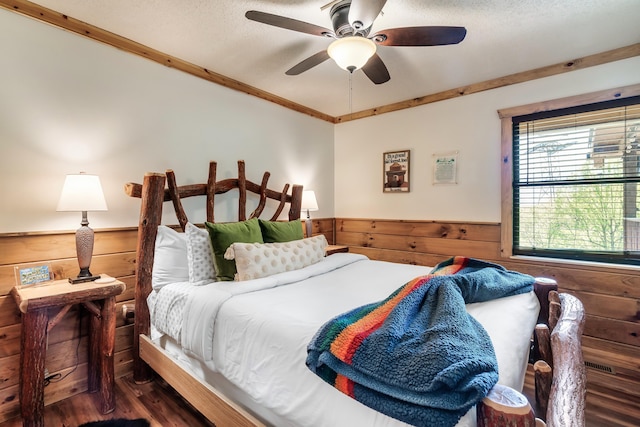 bedroom featuring dark wood-type flooring, a wainscoted wall, wood walls, and a textured ceiling