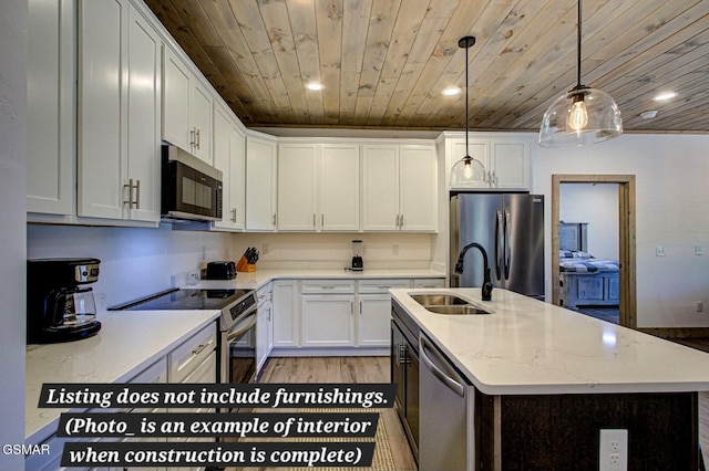 kitchen featuring decorative light fixtures, appliances with stainless steel finishes, white cabinets, a sink, and an island with sink