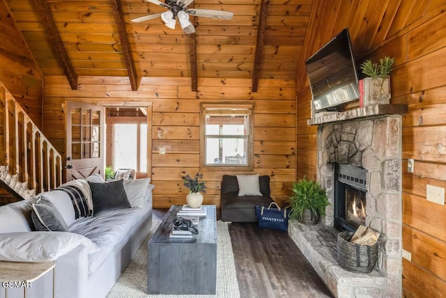 living room featuring lofted ceiling with beams, wood walls, a stone fireplace, wood finished floors, and wooden ceiling