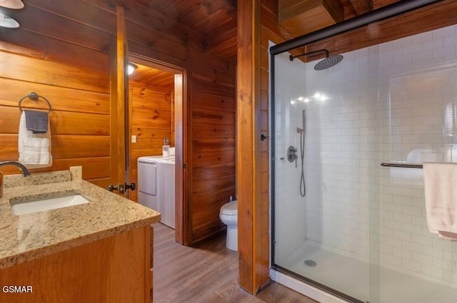 full bathroom with toilet, wooden walls, wood finished floors, vanity, and washer / dryer