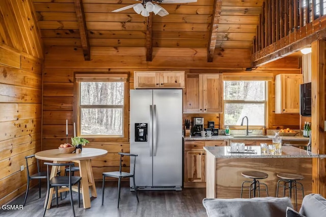 kitchen featuring lofted ceiling with beams, wood walls, a sink, and stainless steel fridge with ice dispenser