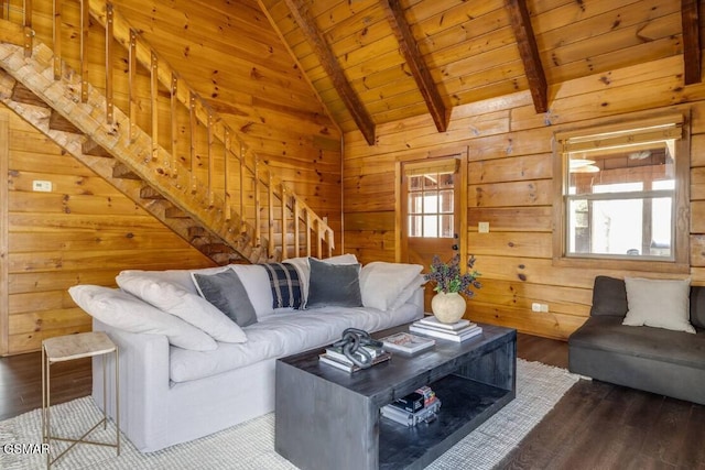 living room with dark wood finished floors, stairway, lofted ceiling with beams, wood ceiling, and wood walls