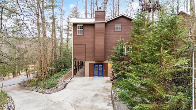 exterior space with french doors, a chimney, and stucco siding