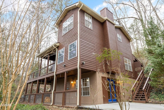 exterior space with stucco siding, a chimney, and stairs