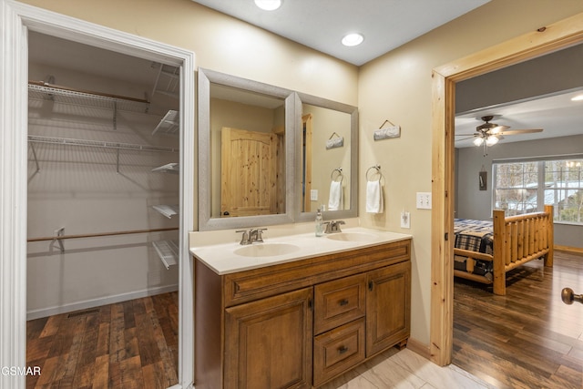 full bathroom featuring ceiling fan, wood finished floors, a sink, and double vanity