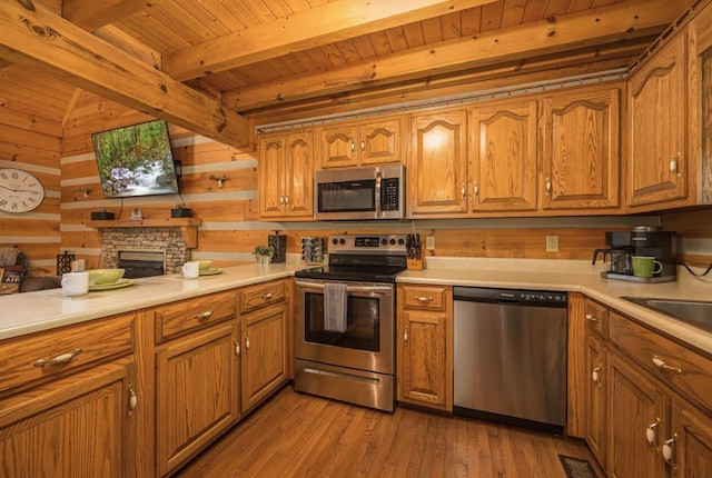 kitchen featuring wooden ceiling, beamed ceiling, wood walls, appliances with stainless steel finishes, and light wood-type flooring