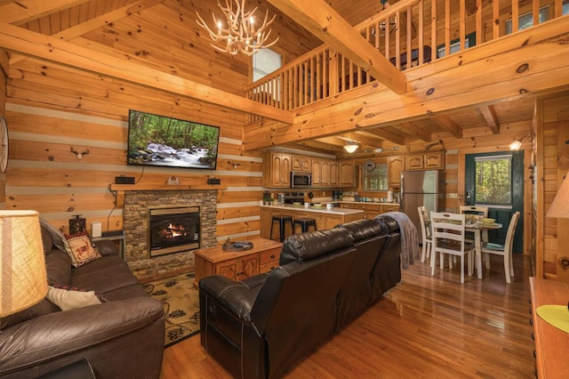 living room featuring wood ceiling, hardwood / wood-style flooring, an inviting chandelier, a stone fireplace, and wood walls