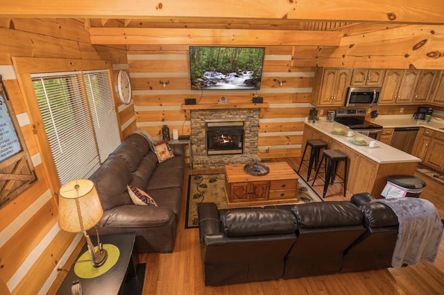 living room with light hardwood / wood-style floors, a stone fireplace, and wood walls