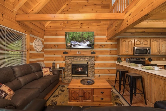 living room featuring wood ceiling, high vaulted ceiling, beamed ceiling, a stone fireplace, and wood walls