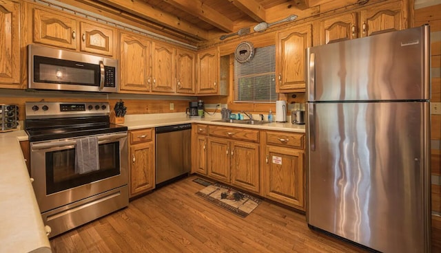 kitchen with beam ceiling, sink, wooden ceiling, light hardwood / wood-style floors, and appliances with stainless steel finishes