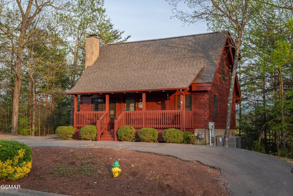 651 Kings Hills Blvd, Pigeon Forge, TN 37863 - view of front of home with covered porch, a shingled roof, asphalt driveway, a chimney, and cooling unit