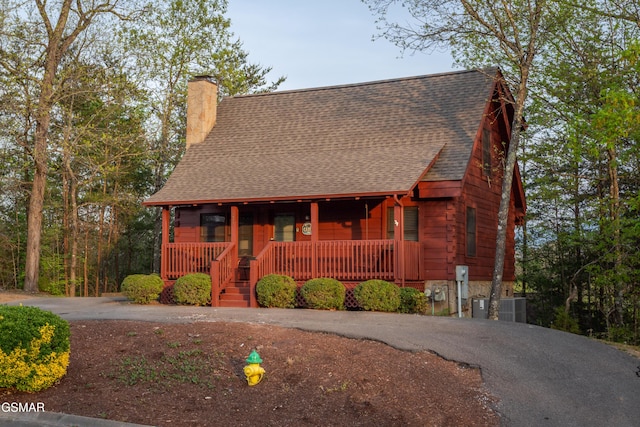 651 Kings Hills Blvd, Pigeon Forge, TN 37863 - view of front of home with covered porch, a shingled roof, asphalt driveway, a chimney, and cooling unit
