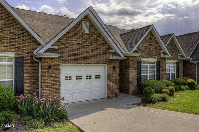 220 River Garden Ct Unit 38, Sevierville, TN 37862 - view of front facade with brick siding, an attached garage, driveway, and roof with shingles