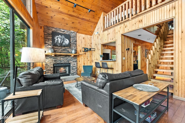 2295 Bluff Mountain Rd, Sevierville, TN 37876 - living area featuring wooden walls, high vaulted ceiling, a stone fireplace, hardwood / wood-style floors, and stairway