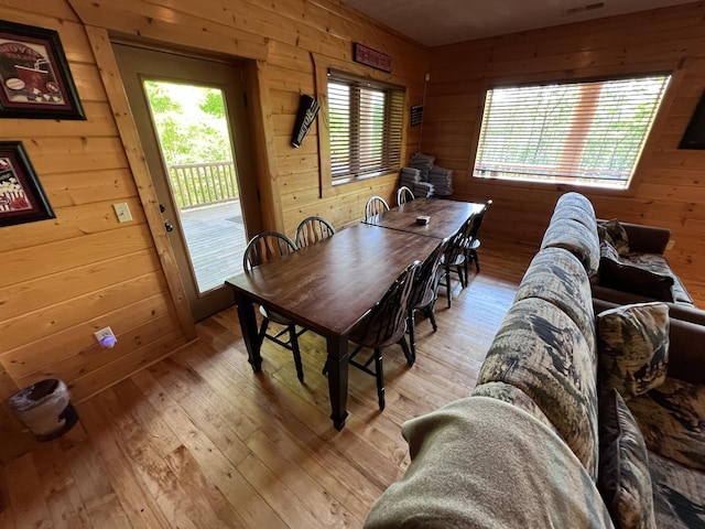 dining area with wooden walls and light hardwood / wood-style flooring