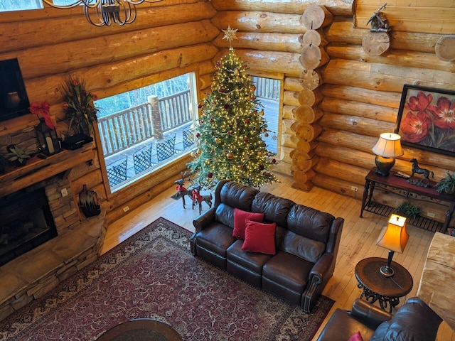 living room with log walls, wood-type flooring, a wealth of natural light, and a fireplace