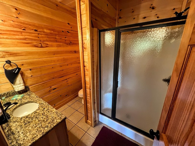 bathroom featuring tile patterned flooring, toilet, wood walls, and an enclosed shower