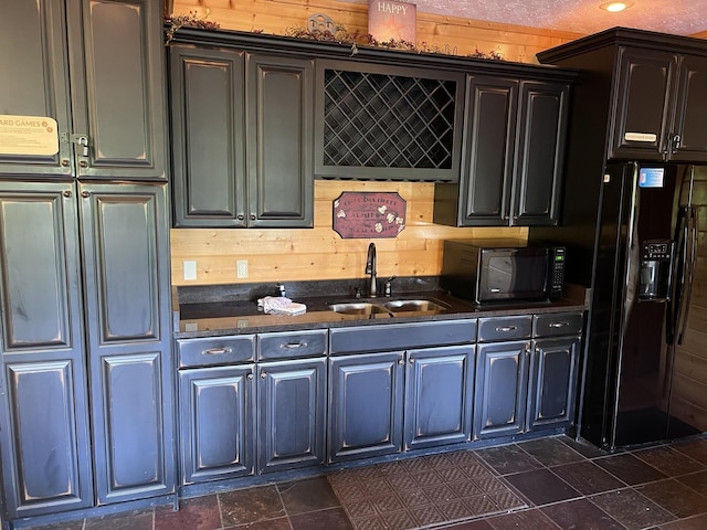 kitchen featuring black appliances, wood walls, and sink