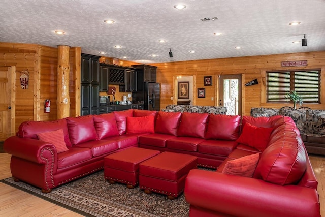 living room featuring hardwood / wood-style floors, a textured ceiling, and wooden walls