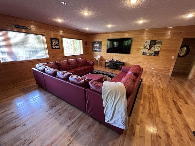 living room with hardwood / wood-style floors, wood walls, and a textured ceiling