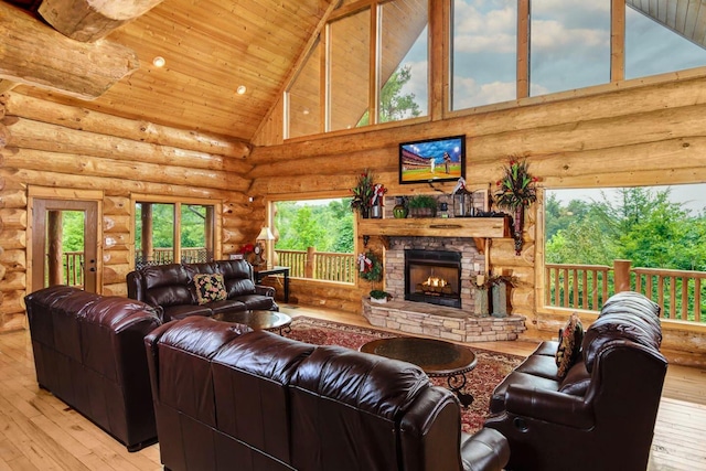 living room with a fireplace, light wood-type flooring, rustic walls, and high vaulted ceiling