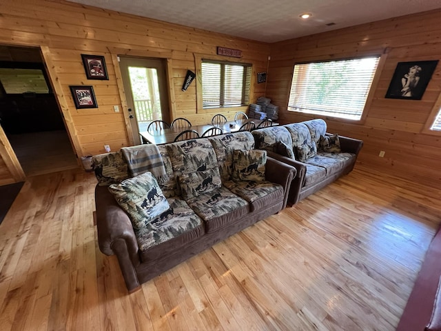 living room featuring wooden walls, a healthy amount of sunlight, and light wood-type flooring