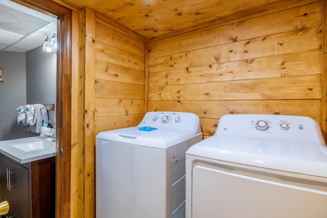 laundry area with wooden walls, sink, and independent washer and dryer