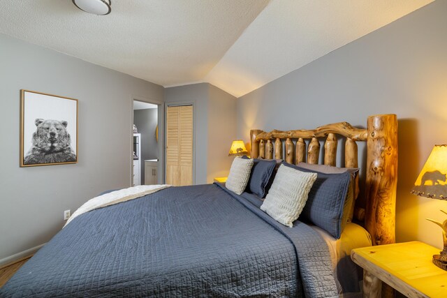 bedroom featuring a textured ceiling, a closet, and lofted ceiling