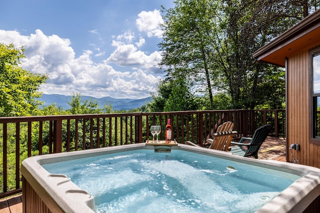 view of swimming pool with a deck with mountain view and a hot tub