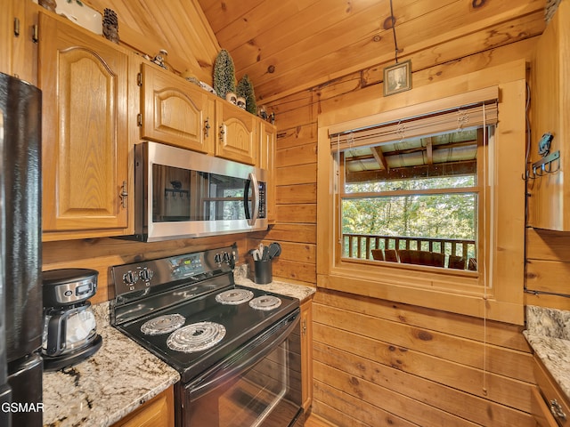 1518 Ridgecrest Dr, Sevierville, TN 37876 - kitchen with stainless steel microwave, electric range, wood walls, light stone counters, and freestanding refrigerator