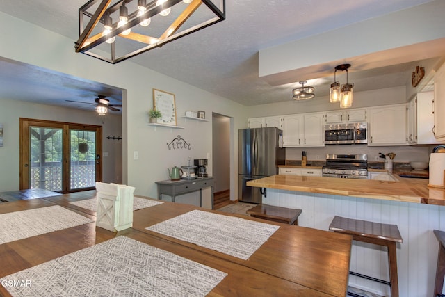 1315 Mccarter Hollow Rd, Sevierville, TN 37862 - kitchen with stainless steel appliances, wood counters, a peninsula, a textured ceiling, and wood finished floors