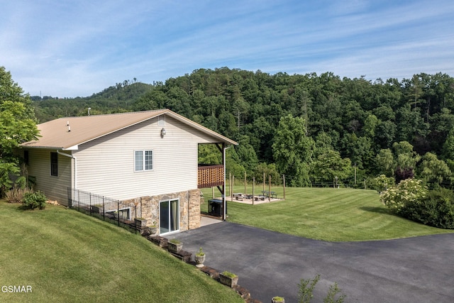 1315 Mccarter Hollow Rd, Sevierville, TN 37862 - view of side of home with stone siding, a patio area, a lawn, and a view of trees