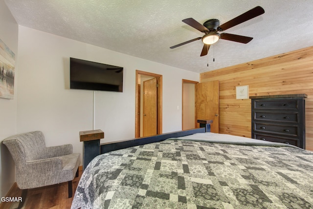 1315 Mccarter Hollow Rd, Sevierville, TN 37862 - bedroom featuring wood walls, wood finished floors, a textured ceiling, and a ceiling fan
