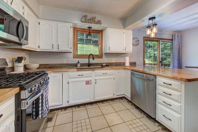 1315 Mccarter Hollow Rd, Sevierville, TN 37862 - kitchen with stainless steel appliances, a peninsula, white cabinetry, and light tile patterned floors