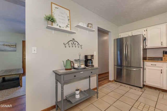 1315 Mccarter Hollow Rd, Sevierville, TN 37862 - kitchen featuring freestanding refrigerator, white cabinetry, a textured ceiling, and light tile patterned floors