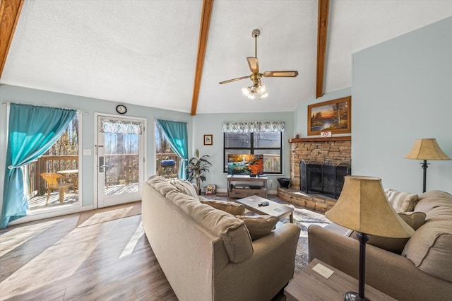 living room featuring vaulted ceiling with beams, ceiling fan, a fireplace, and hardwood / wood-style flooring