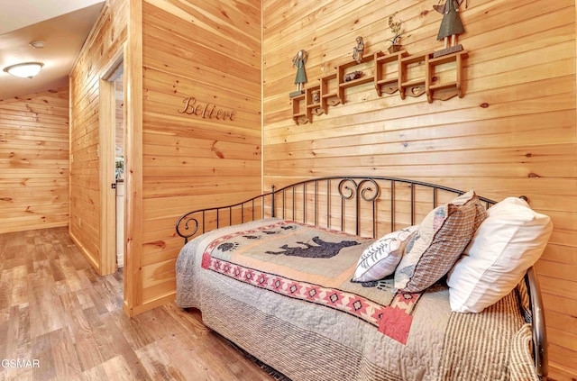 bedroom featuring wood finished floors and wooden walls