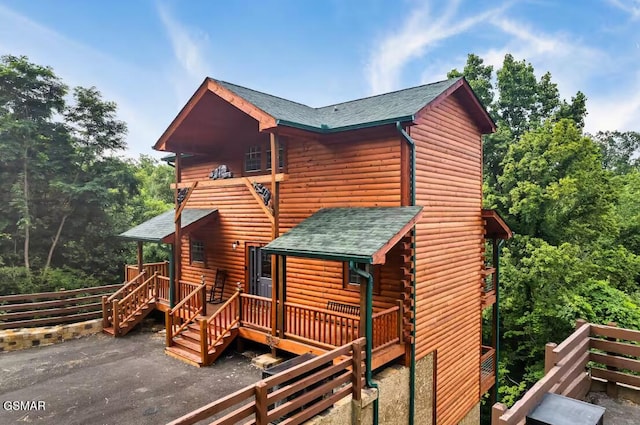 exterior space featuring roof with shingles and a deck