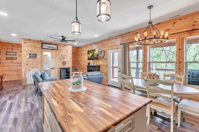 dining space with wood finished floors, wood walls, visible vents, and recessed lighting
