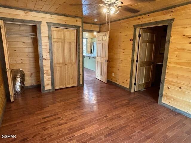 interior space with wooden walls, ceiling fan, wooden ceiling, and dark hardwood / wood-style floors