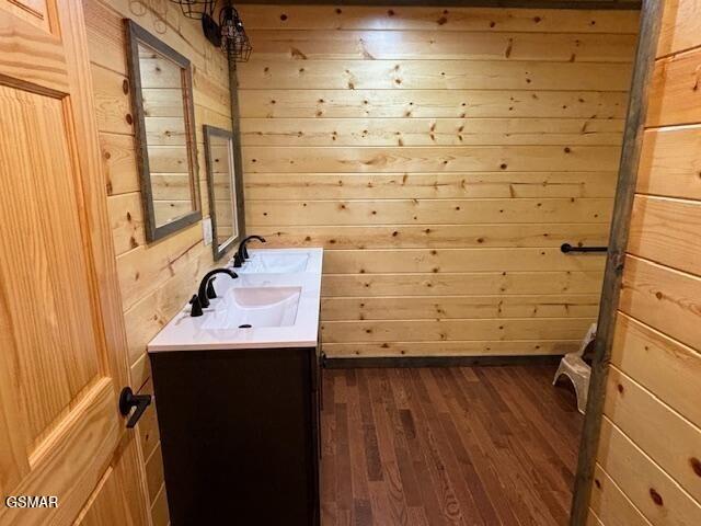 bathroom with wooden walls, hardwood / wood-style floors, and vanity