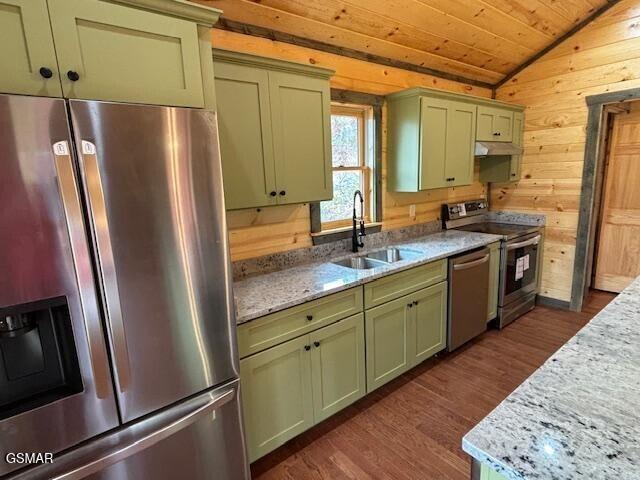 kitchen featuring stainless steel appliances, green cabinets, sink, lofted ceiling, and wood walls