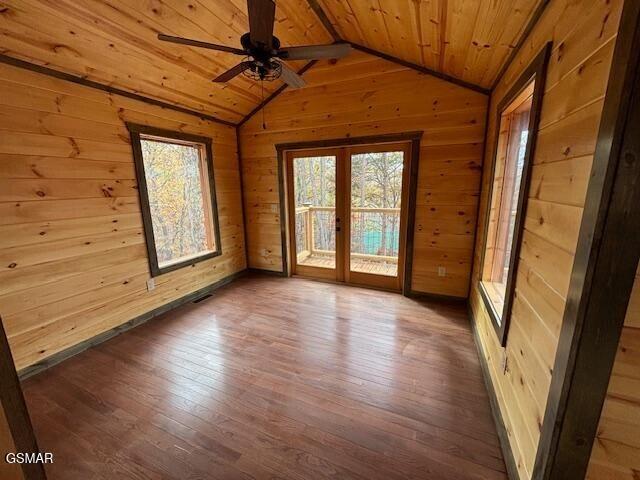 spare room featuring wood walls, lofted ceiling, wooden ceiling, ceiling fan, and wood-type flooring