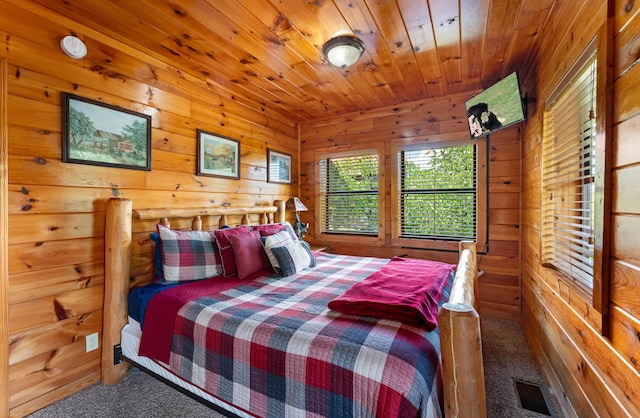 carpeted bedroom featuring wood ceiling, visible vents, and wooden walls