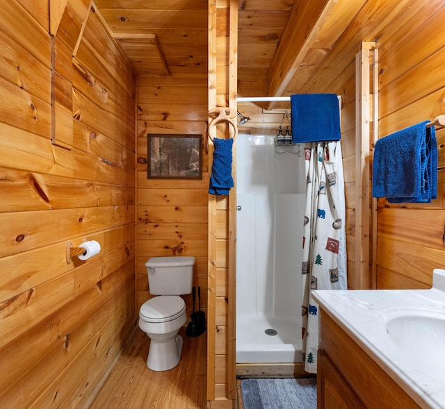 full bathroom with a stall shower, toilet, wood finished floors, vanity, and wood walls