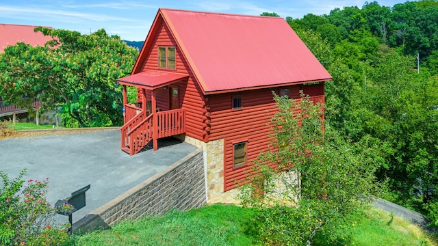 view of home's exterior with stone siding, metal roof, and log exterior