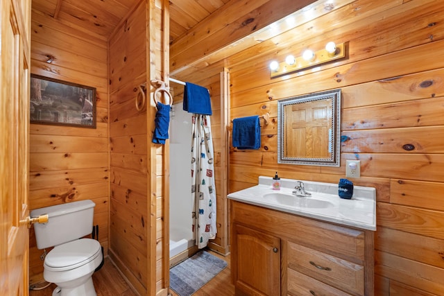 full bath with curtained shower, toilet, wood walls, wood finished floors, and vanity