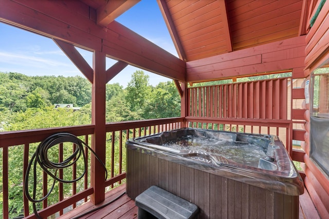 wooden terrace with a hot tub and a forest view